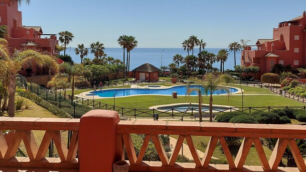 A resort with a pool, palm trees, and a view of the ocean. - Quiet and Luxurious Apartment on the Beach (Torrox)