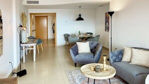 A living room with a sofa, armchairs, a coffee table, and a dining area with a table and chairs. - Quiet and Luxurious Apartment on the Beach (Torrox)