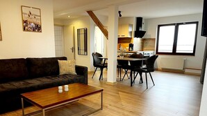 A living room with a sofa, coffee table, and dining area with chairs. - "Lindenblatt" 3-room apartment, 2 bathrooms, Büsum (4km), parking lot, North Sea (Oesterdeichstrich)