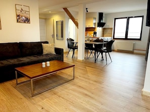 A living room with a sofa, coffee table, and dining area with chairs.