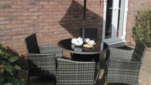 En patio med fletmøbler, et bord og en stor parasol.