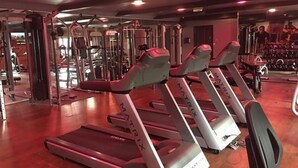 Et fitnesscenter med løbebånd, træningsmaskiner og et spejl.