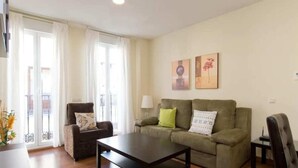 Un salon comprenant un canapé, un fauteuil, une table basse et un balcon avec des rideaux.