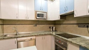 Une cuisine avec des meubles blancs, un four à micro-ondes, une cuisinière et un lave-vaisselle.