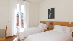 Une chambre d’hôtel avec deux lits, une tête de lit en bois, une table de chevet avec une lampe, un bureau et une chaise.