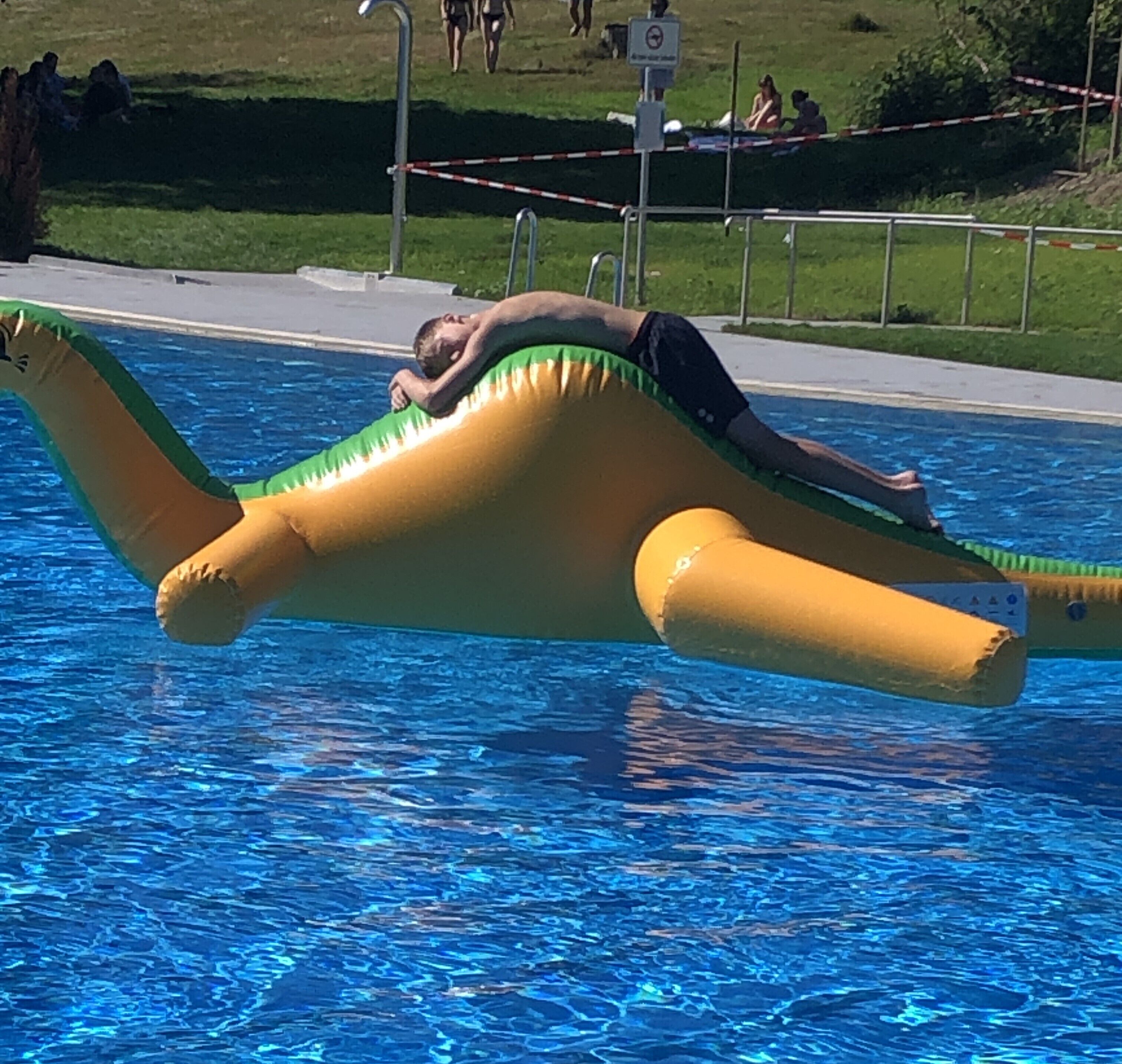 A person lying on an inflatable boat in a swimming pool.