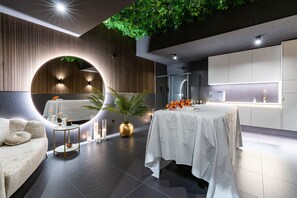 Una habitación de hotel moderna con una zona de estar circular, una mesa de comedor y una cocina.