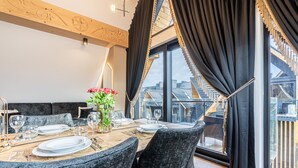 A dining area with a table set for four, large windows with curtains, and a view of the outside. - Aparthotel Diamond SPA Aqua (Bukowina Tatrzanska)