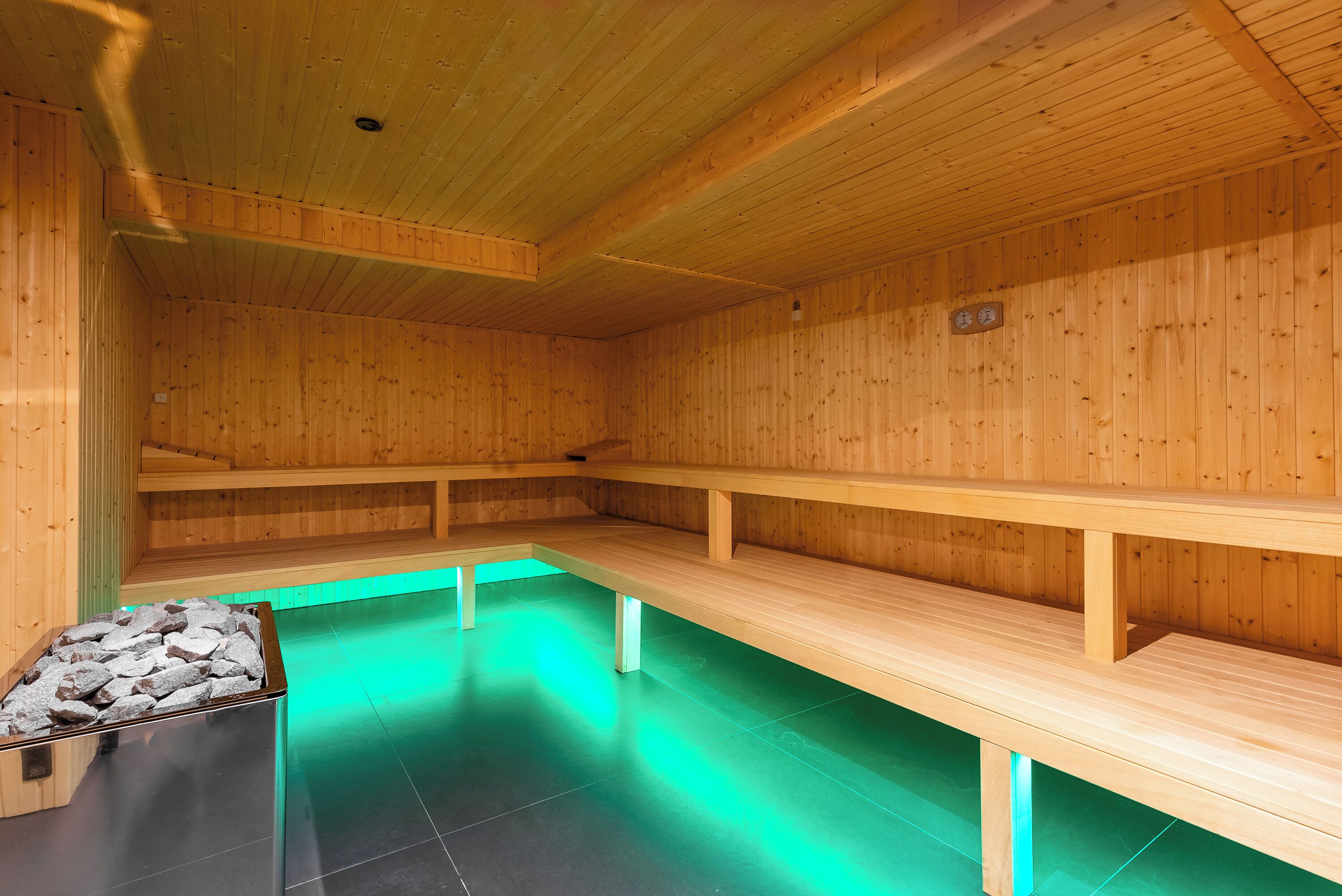 A sauna room with wooden benches and a stone basin.