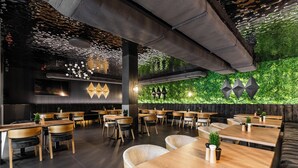 A modern restaurant with wooden tables and chairs, a green wall with plants, and geometric wall decorations. - Aparthotel Diamond SPA Aqua (Bukowina Tatrzanska)