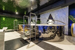 A modern indoor pool area with a glass wall, a metal pool ladder, and a green wall with plants. - Aparthotel Diamond SPA Aqua (Bukowina Tatrzanska)