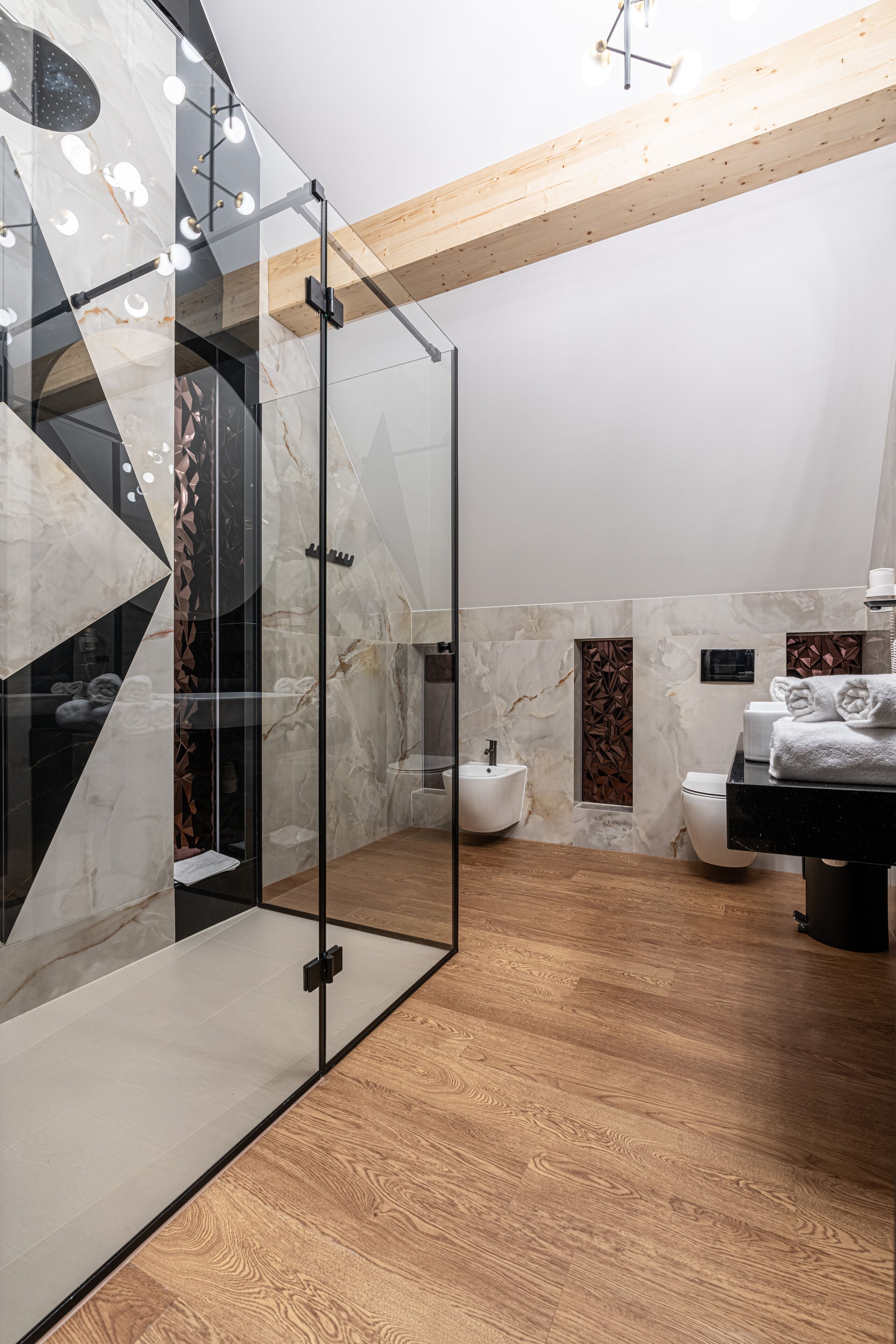 Un baño moderno con ducha de vidrio, paredes de mármol y suelo de madera.