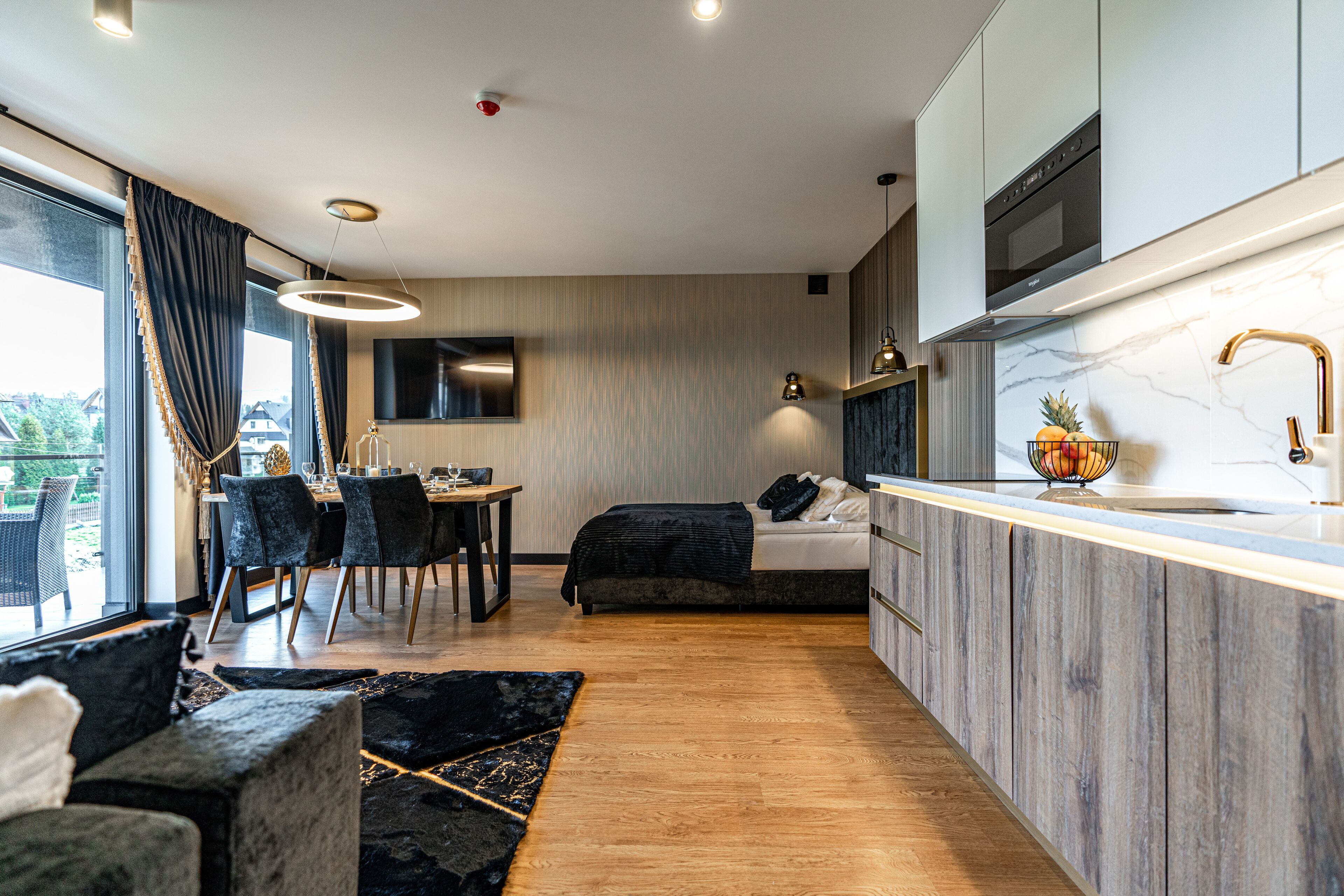 A modern kitchen with a dining area, a bed, and a view of the outdoors.