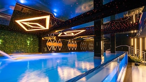 A modern indoor swimming pool with geometric light fixtures and a green wall. - Aparthotel Diamond SPA Aqua (Bukowina Tatrzanska)