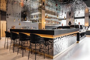 A modern bar area with a patterned wall, bar stools, and shelves stocked with bottles. - Aparthotel Diamond SPA Aqua (Bukowina Tatrzanska)