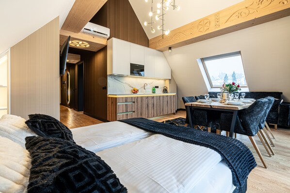 A modern loft bedroom with a large bed, a dining area, and a kitchen.