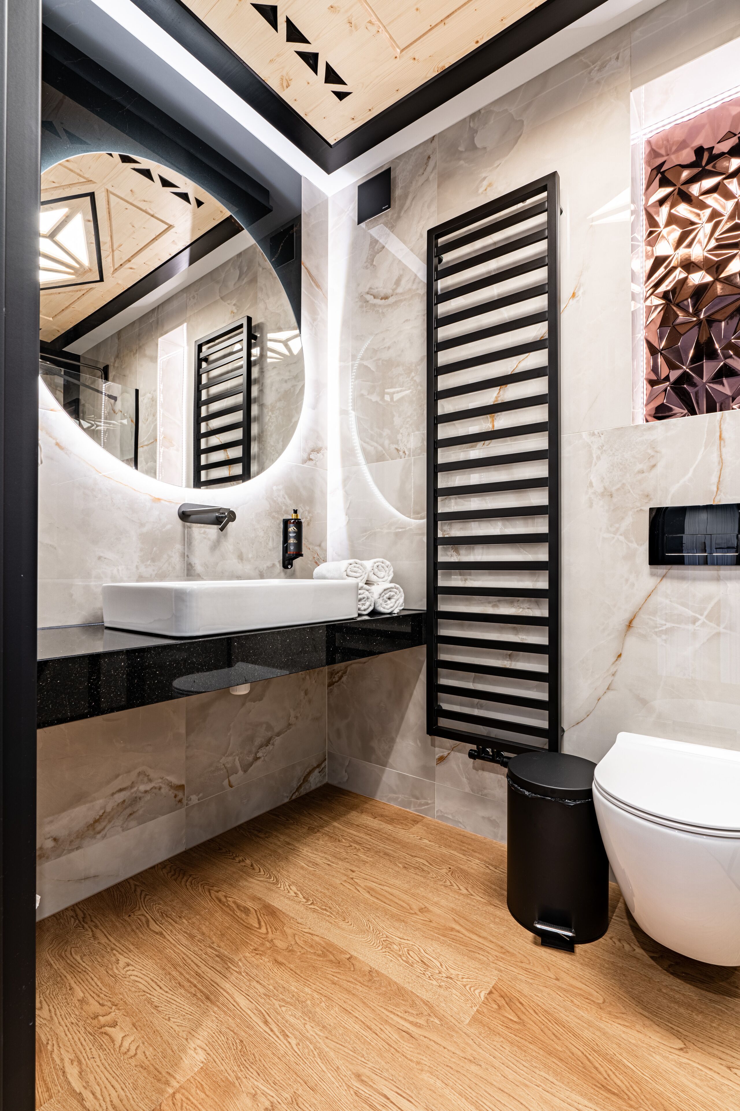 A modern bathroom with a marble sink, black countertop, and a toilet.