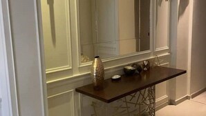 Een moderne hal met een grote spiegel, een donker houten console en een decoratieve vaas.