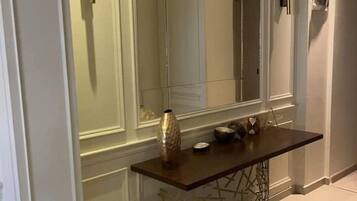A modern hallway with a large mirror, a dark wooden console table, and a decorative vase.