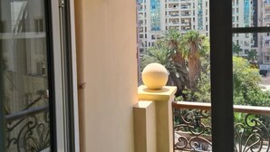 Een balkon met een decoratieve lamp, een bolvormige decoratie en uitzicht op hoogbouw.