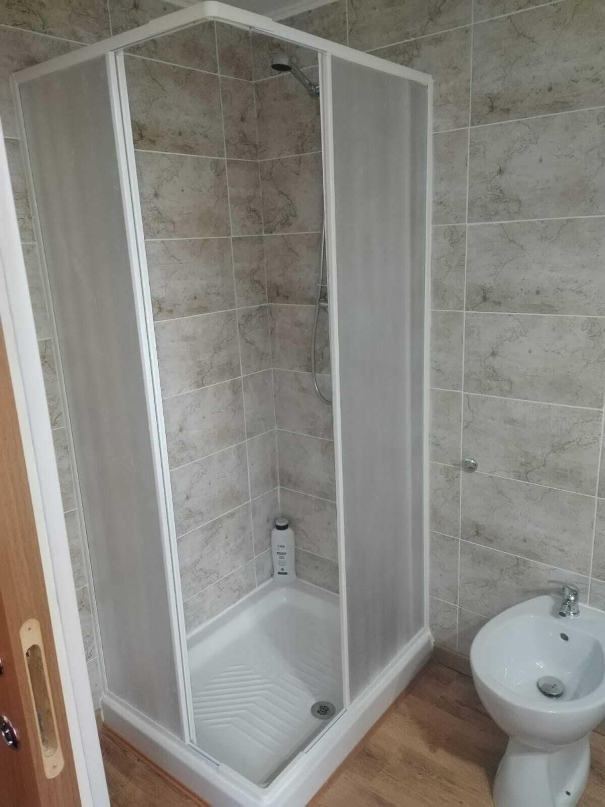 Un baño con cabina de ducha, un bidé y paredes de azulejos.