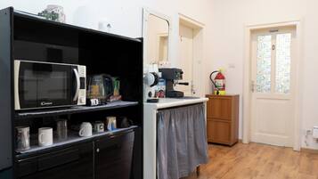 Een kleine keuken met een magnetron, koffiezetapparaat en een koelkast.