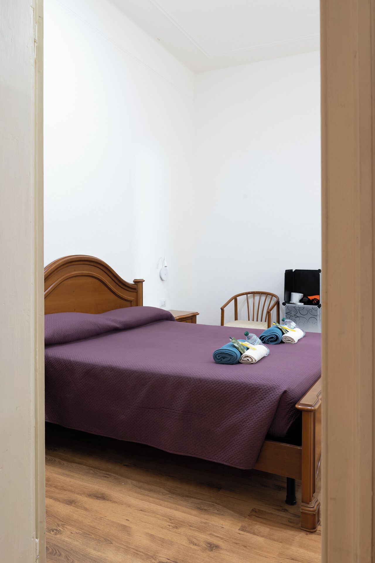 Una camera da letto con un letto di legno, una sedia, un tavolino e una valigia.