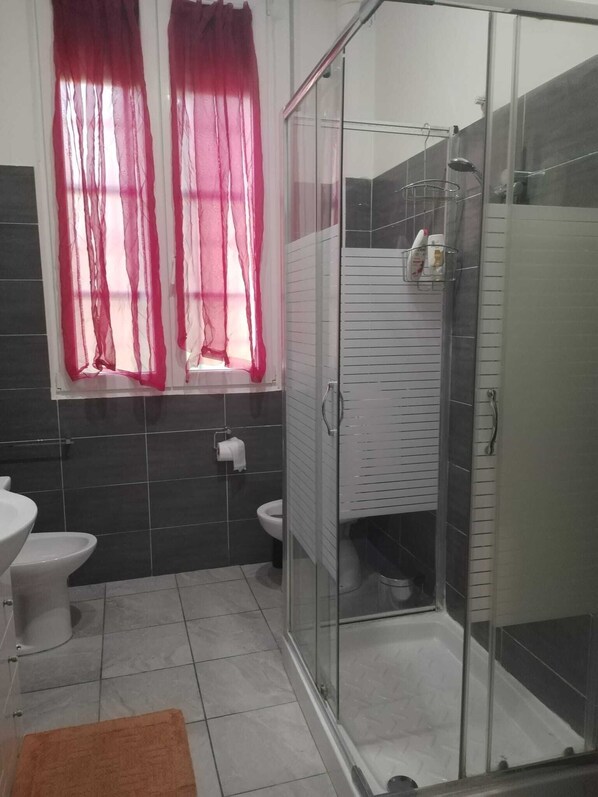 Un baño moderno con cabina de ducha de vidrio, inodoro y lavamanos.