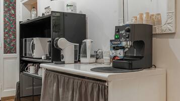 A kitchenette with a microwave, kettle, coffee machine, and a small refrigerator.
