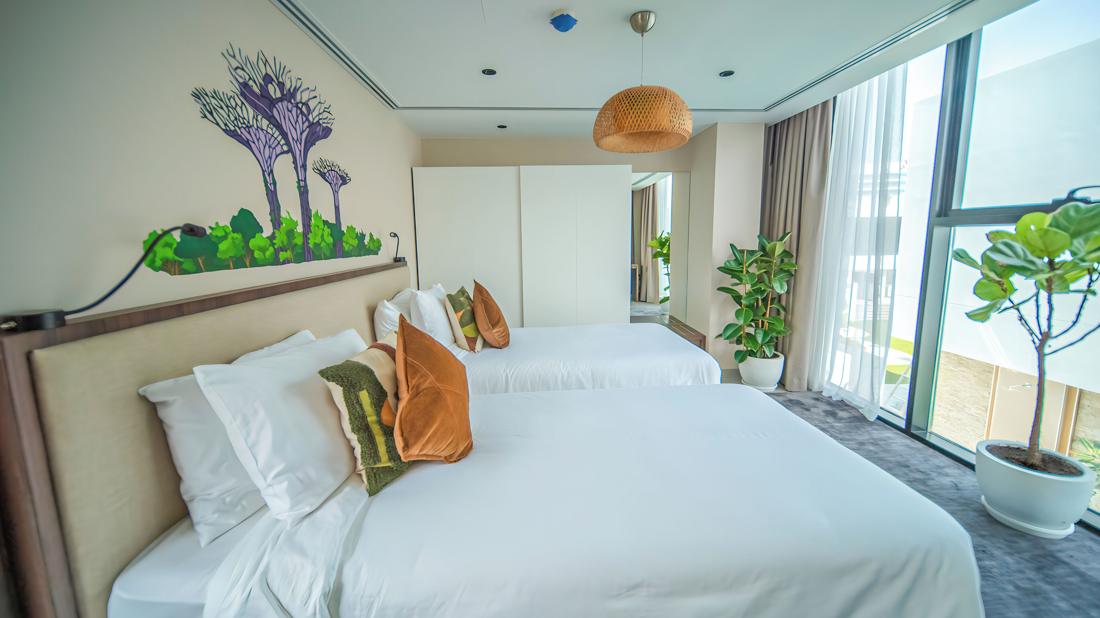 Ein Hotelzimmer mit zwei Betten, einem großen Fenster und einem Wandgemälde.