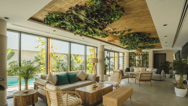A spacious living area with a large window, a sofa set, a coffee table, and wicker furniture. - Nas House Private Villas (Dubai)