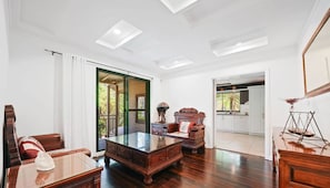 Amplia habitación con un escritorio de madera grande, un sofá y una mesa de comedor. Se ve una cocina y un balcón.