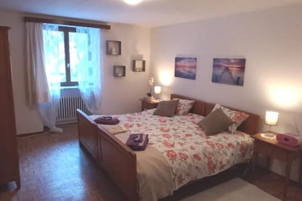 Een slaapkamer met een bed, nachtkastjes, een raam met gordijnen en aan de muur hangende foto's.
