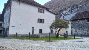 Un bâtiment traditionnel avec une façade blanche, un mur en pierre et une rue pavée.