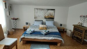 Une chambre à coucher avec un lit, des tables de chevet, un plancher en bois, une œuvre d’art accrochée au mur et une menorah.