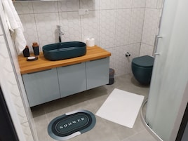 Un baño moderno con encimera de madera, lavamanos y retrete.