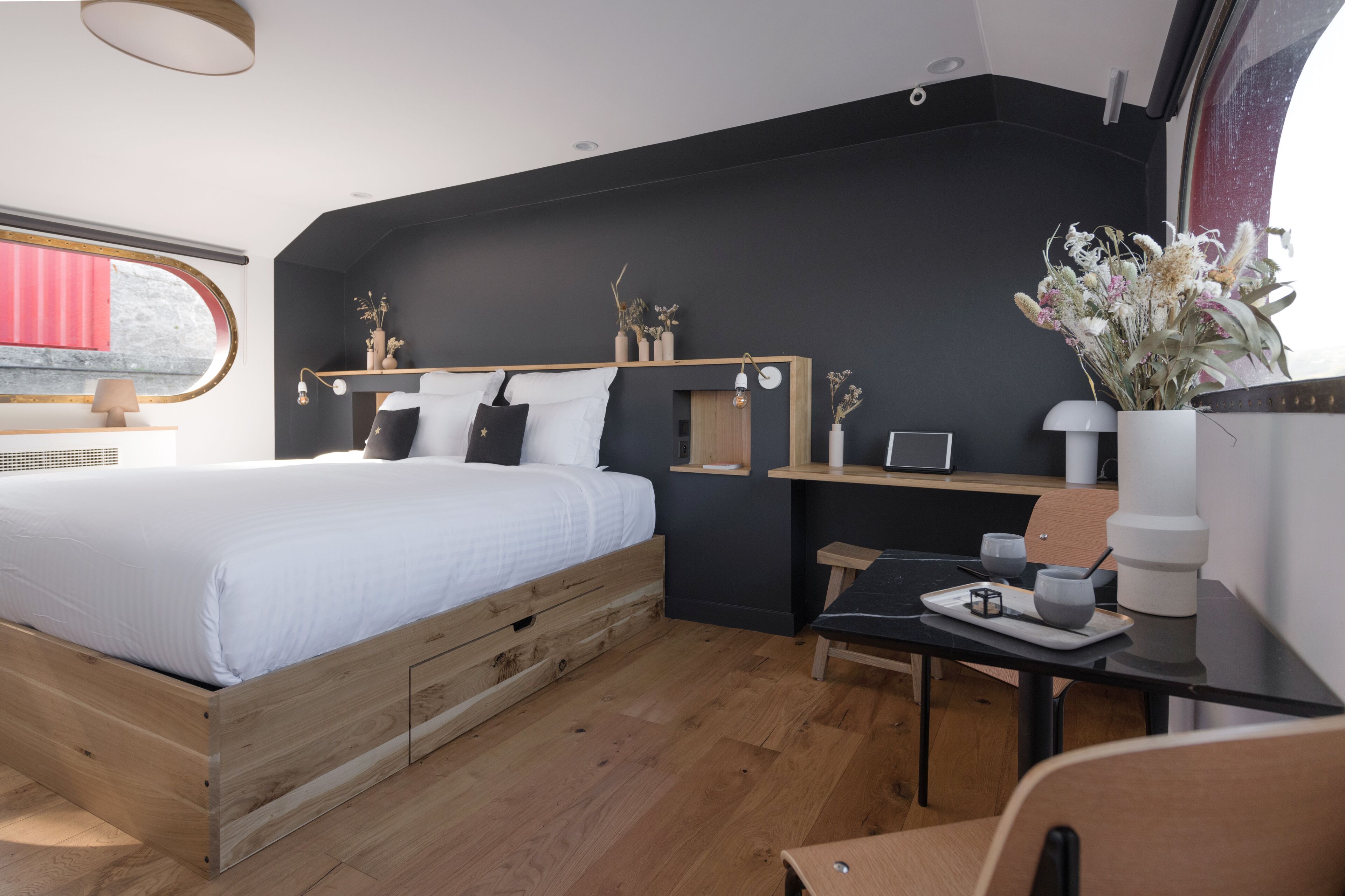 Un dormitorio moderno con una cama de madera, un escritorio y una ventana con cortina roja.