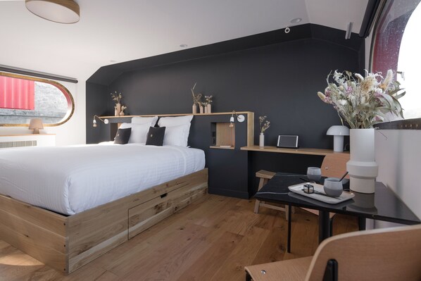 A modern bedroom with a wooden bed, a desk, and a window with a red curtain. - LA PENICHE - Bed And Bicycle - Tournon (Tournon-sur-Rhone)