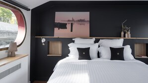 A modern bedroom with a large bed, a cityscape painting, and a view of a body of water through a window. - LA PENICHE - Bed And Bicycle - Tournon (Tournon-sur-Rhone)