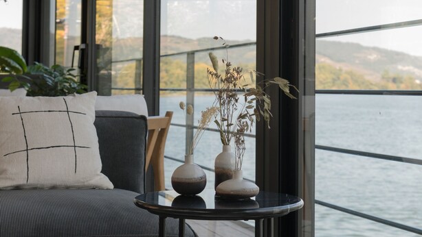 A modern living room with a sofa, a small table, and a view of a body of water. - LA PENICHE - Bed And Bicycle - Tournon (Tournon-sur-Rhone)