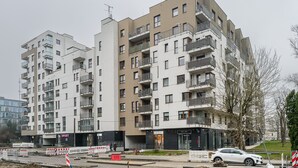 Un immeuble résidentiel à plusieurs étages, doté de balcons, d’une entrée bien visible et de barrières de chantier.
