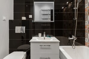 Ein modernes Badezimmer mit einem weißen Waschbecken, einem Spiegel darüber, einer Toilette und einer Duschkabine.