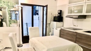 Hotellihuone, jossa on sänky, tuoli, työpöytä, mikroaaltouuni, kahvinkeitin ja näkymä kadulle.