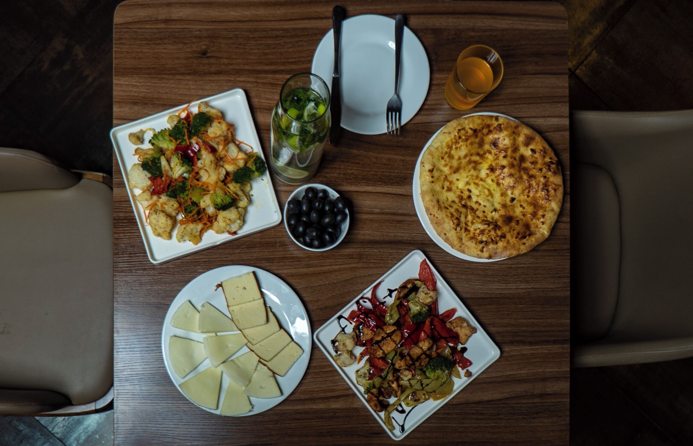 A dining table with various dishes, including pizza, cheese, and vegetables.