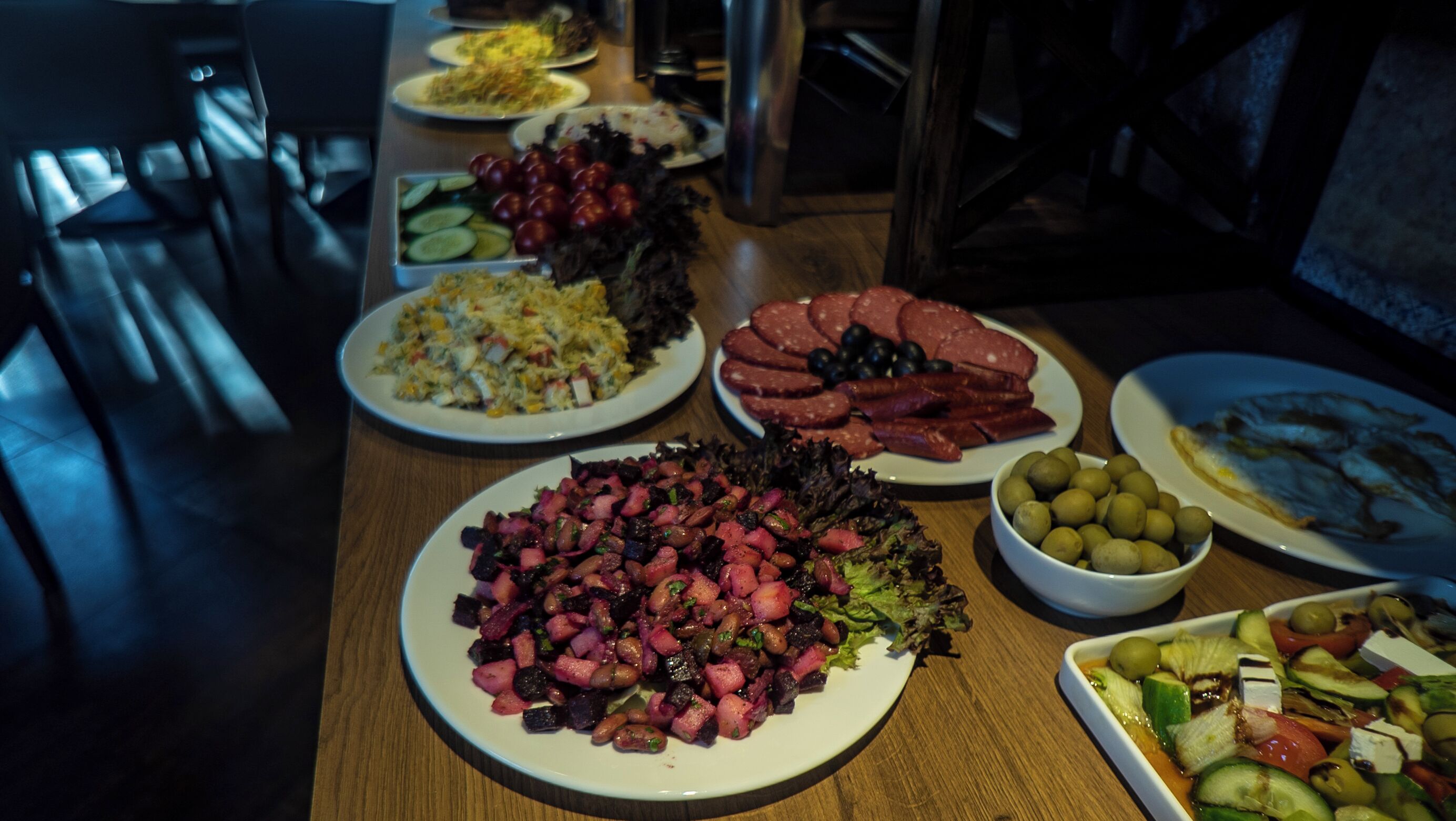 A dining table with various dishes, including salads, meats, and vegetables.