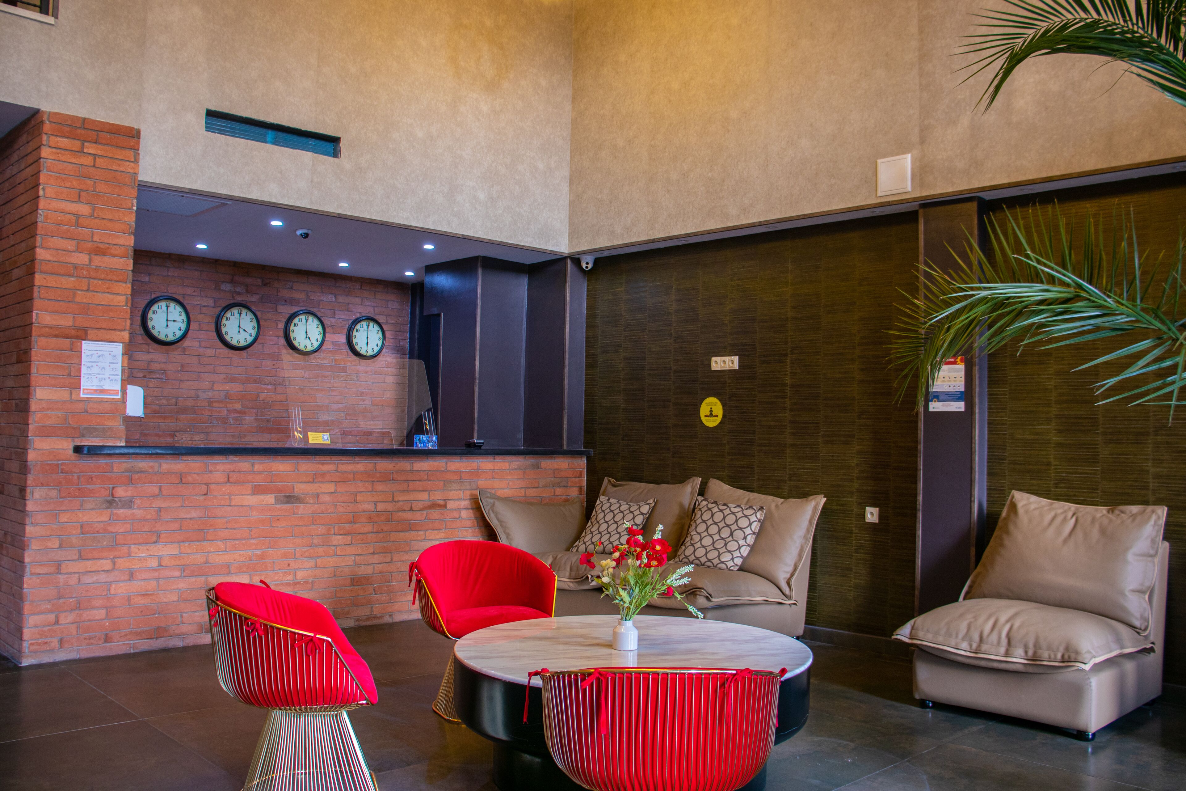 Um hall de entrada com balcão de recepção, um sofá, duas cadeiras e uma mesa redonda com um vaso de flores.