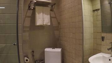 Un baño con cabina de ducha de vidrio, inodoro, lavabo y toallero con toallas.