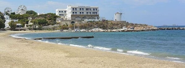 A beach with a building that has a windmill and a sign that says "PARKING HOTEL".