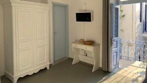 A room with a white wardrobe, a small white desk with a flat-screen TV, and a balcony with a metal railing. - Au Cœur de Parikia , Appartement Cosy Avec Balcon (Parikiá)