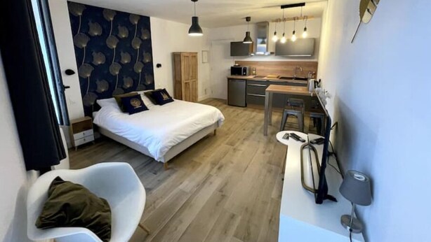 Et lille hotelværelse med seng, skrivebord, stol, tekøkken og badeværelse.
